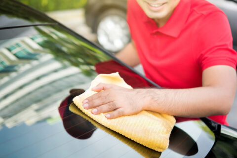 穿着红色T恤的男人擦拭汽车挡风玻璃